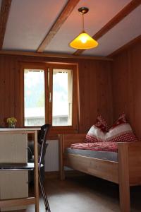 a bedroom with a bed and a table and windows at Harri's BnB in Kandersteg, Ferienwohnung in Kandersteg