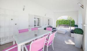 Vila Mar في كامبريلس: مطبخ مع كراسي وردية وطاولة بيضاء