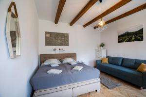 1 dormitorio con 1 cama y 1 sofá azul en Miliő Apartman Badacsony, en Badacsonytördemic