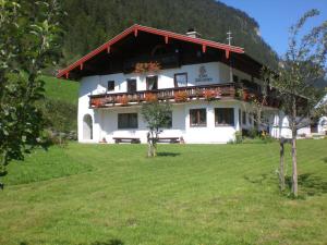 - un bâtiment blanc avec un balcon dans un champ dans l'établissement Kilianhof, à Berchtesgaden