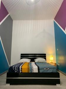 1 dormitorio con 1 cama con una pared colorida en L’ÉMERAUDE 3 en Châlons-en-Champagne