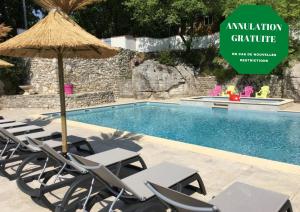 um grupo de cadeiras e um guarda-sol junto a uma piscina em Camping Chalets Les Chênes Verts em Vogüé