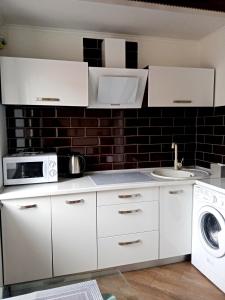 a white kitchen with a microwave and a sink at 1-room Studio center in Cherkasy