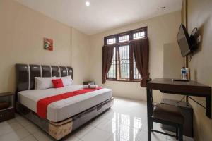 a bedroom with a bed and a desk and a television at RedDoorz near RS Adam Malik Medan 2 in Sunggal