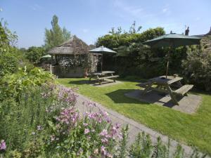 um jardim com duas mesas de piquenique e um guarda-sol em The Masons Arms em Yeovil