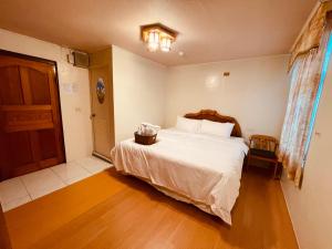 a bedroom with a white bed and a wooden floor at Shexia Liyu Hot Spring in Checheng