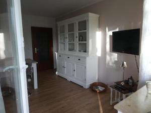 a living room with a large white cabinet with a flat screen tv at Ferienwohnung Am Hirschpark in Bad Pyrmont