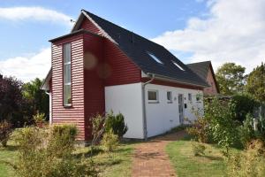 a small red and white house with a garage at Ferienhaus Backbord und Steuerbord in Börgerende-Rethwisch