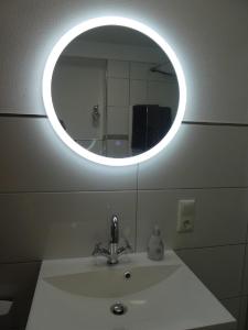 a bathroom sink with a round mirror above it at Ferienwohnung Am Hirschpark in Bad Pyrmont