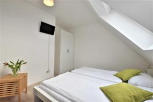 a bedroom with a white bed with green pillows at Ferienhaus Backbord und Steuerbord in Börgerende-Rethwisch