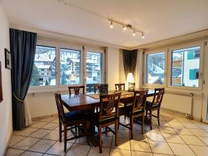 ein Esszimmer mit einem Tisch, Stühlen und Fenstern in der Unterkunft L'Attila - Big and cozy flat in the Center 7 beds in Zermatt