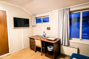 um quarto com uma secretária, uma televisão e janelas em Skaidi Hotell em Skaidi