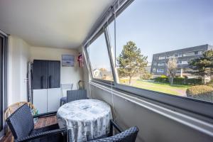 een tafel en stoelen in een kamer met een raam bij Le Pavois - appartement à 50 mètres de la mer in Bernières-sur-Mer