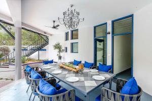 a dining room with a long table and blue chairs at StayVista at Ananta in Bangalore