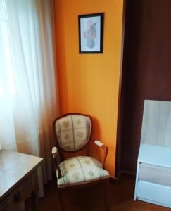 a chair in a room with an orange wall at Hostal Fisterra in Lugo