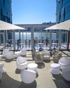 a patio with white chairs and tables on a building at De Homme Hotel in Busan