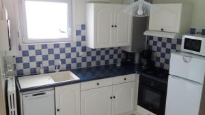 a kitchen with white cabinets and blue and white tiles at gîte cœur de baie in Le Crotoy