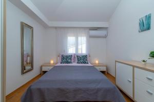 Un dormitorio con una cama con almohadas azules y una ventana en Apartment Angela, en Trogir