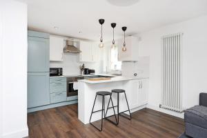 uma cozinha com armários brancos e dois bancos de bar em JOIVY Contemporary Royal Mile Apartment with Balcony em Edimburgo