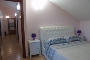 a bedroom with a white bed with blue pillows and a table at Stella Maris Holidays in Maiori
