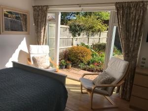 a bedroom with a bed and two chairs in front of a window at Garden Studio in Marlow