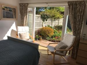 ein Schlafzimmer mit einem Bett und zwei Stühlen vor einem Fenster in der Unterkunft Garden Studio in Marlow