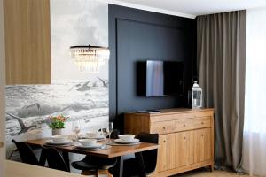 Un comedor con una mesa con sillas y un televisor. en Apartamenty Royal Maris 3 - najlepsza lokalizacja w Ustce, blisko plaży i portu, bezpłatny parking, ścisłe centrum, en Ustka