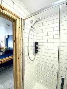 a shower with a glass door in a bathroom at Stylish, cosy studio in Carmarthen town centre in Carmarthen