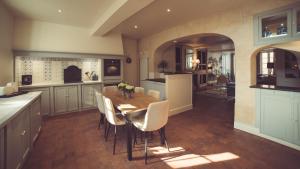 a kitchen with a wooden table and white chairs at La Villa Celestine in Chablis