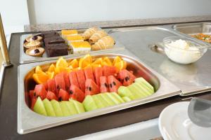 a tray of fruit on a counter with other desserts at Dioni Hotel in Adelianos Kampos