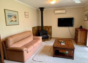 a living room with a couch and a wood stove at Leeward 'tranquil beachfront' in Kingscote
