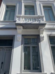 - un bâtiment blanc avec des fenêtres et un balcon dans l'établissement Brussels Guest House, à Bruxelles