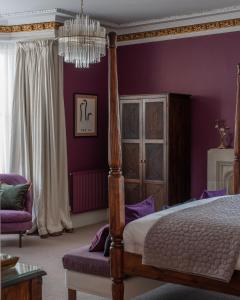 a bedroom with purple walls and a bed and a chandelier at Tigh Na Leigh in Alyth