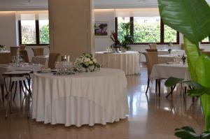 ein Esszimmer mit weißen Tischen und Stühlen mit Blumen darauf in der Unterkunft Hotel Europa in Rende