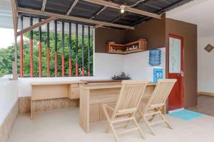 eine Küche mit 2 Stühlen und einen Schreibtisch mit einem Fenster in der Unterkunft RedDoorz Syariah near Kota Cinema Mall Jatiasih 