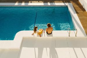 2 femmes assises à côté d'une piscine dans l'établissement Punta Paradiso, à Punta del Hidalgo