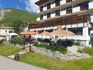 a restaurant with tables and umbrellas in front of a building at Le Terril Blanc in Tignes