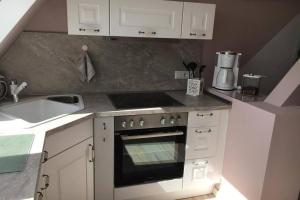 a white kitchen with a stove and a sink at Ferienwohnung Herzmuschel in Aventoft
