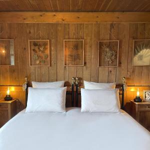 a bed with white pillows in a room with wooden walls at Domaine de Sault in Dore-lʼÉglise