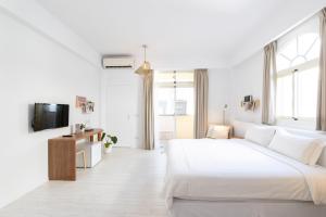 a white bedroom with a large bed and a tv at OwlStay The Salt in Hualien City
