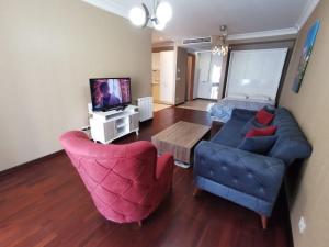 sala de estar con sofá, sillas y TV en CTS Elysium Residence Taksim, en Estambul