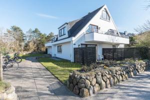 a white house with a stone retaining wall at Schau-ins-land Fewo Wenningstedt in Wenningstedt