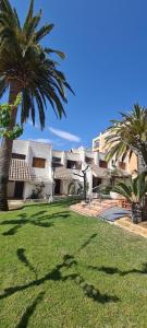 a building with palm trees in front of a yard at Adosado con piscina a 50 metros de la playa - Las Fuentes ALBERT VILLAS in Alcossebre