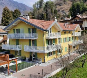 a yellow house with white balconies on a street at La mansarda di Rossella in Pieve Di Ledro