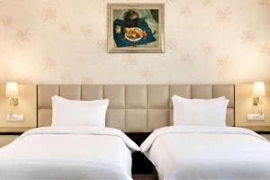 a hotel room with two beds and a painting on the wall at Wyndham Tashkent in Tashkent