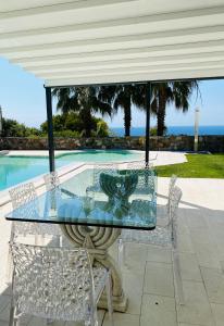 una mesa de cristal y sillas en un patio con piscina en Villa Monet en Bordighera