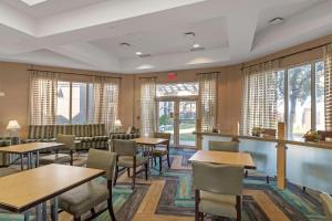a restaurant with tables and chairs and windows at La Quinta by Wyndham Ft. Lauderdale Airport in Hollywood