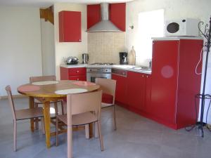 een keuken met rode kasten en een tafel en stoelen bij Gîtes du Manoir de Goandour in Crozon