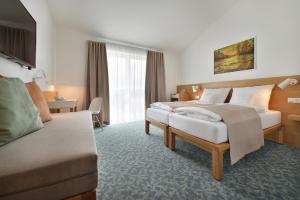 a hotel room with two beds and a couch at Wellness Hotel Happy Star in Hnanice