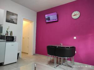a room with a purple wall with a table and a clock at Apartmani QUATTRO in Starigrad
